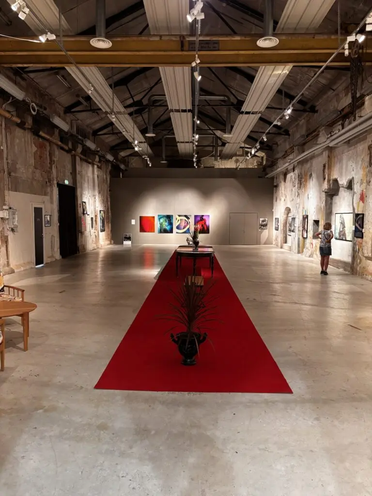 Interiör av Galleri Skutestan i Håverud, en rymlig konsthall i en gammal industrilokal med råa betongväggar, högt i tak och pågående konstutställning.